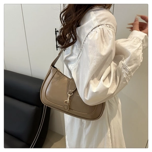 Detail der hellbraunen Hobo-Tasche mit Goldschnalle auf weißem Spitzenhemd