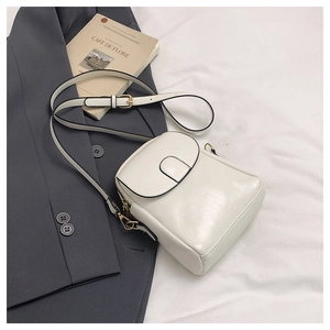 Detail of white mini crossbody bag with golden metal hardware and adjustable strap