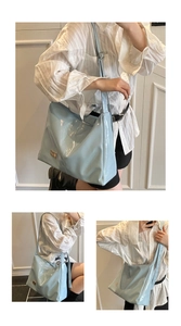 Detail view of glossy light blue tote bag with metallic plate and wide shoulder strap