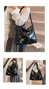 Detailed view of glossy black tote bag with polished finish and gold logo plate