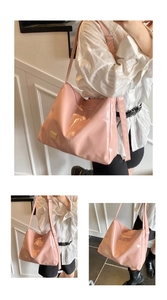Detailed view of pink glossy patent leather shoulder bag with gold metal logo plaque