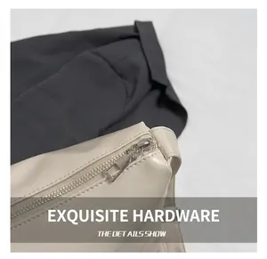 Detail shot of a silver metal zipper and fine leather texture on an off-white tote bag