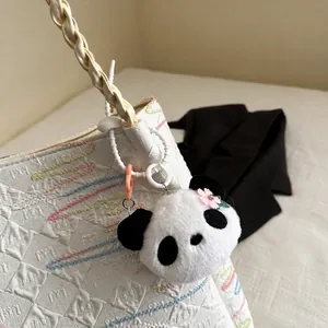 Close-up of white textured bucket bag with wavy stitching and a cute panda plush charm