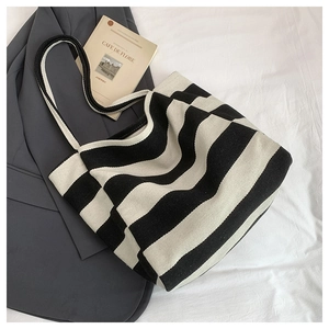 Detailed top view of a striped canvas tote bag with a vintage postcard on white linen