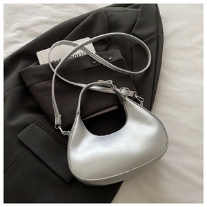 Détails du sac demi-lune argenté effet métallisé posé sur une veste de costume noire