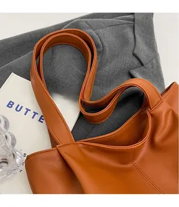 Close-up of brown litchi grain leather tote bag with smooth matching shoulder straps