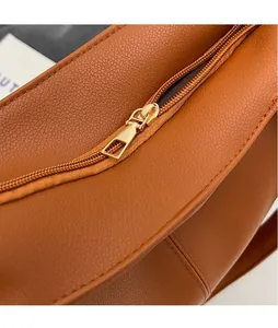 Detailed close-up of premium gold-toned zipper and pebble leather texture on brown tote bag