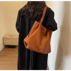 Close-up of caramel faux leather tote bag showing textured surface and soft drape