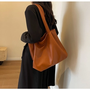 Detail of vintage large-capacity caramel tote bag shown on model for size and scale