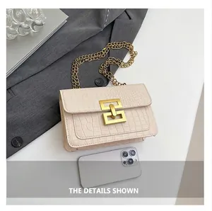 Detailed close-up of cream crocodile pattern bag with gold clasp and chain strap