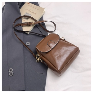 Detailed top view of a brown vintage crossbody bag with gold hardware on a suit jacket