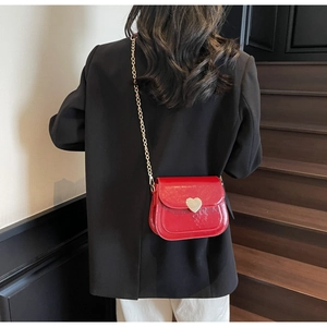 Red glossy faux leather crossbody bag featuring a gold heart buckle and fine chain strap