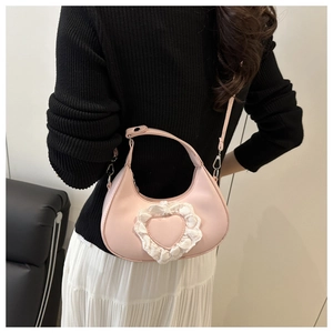 Borsa a cuore rosa con pizzo bianco indossata a tracolla da una modella