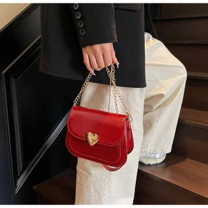 Detailansicht der roten Lackleder-Umhängetasche mit goldenem Herzverschluss und Kette
