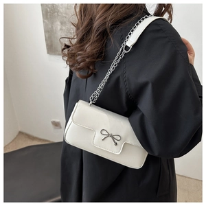 Détail du sac à bandoulière blanc avec boucle à nœud argenté et chaîne en métal élégante