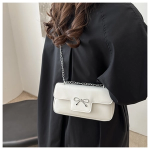 Détail du sac à bandoulière blanc avec nœud argenté et bandoulière en chaîne