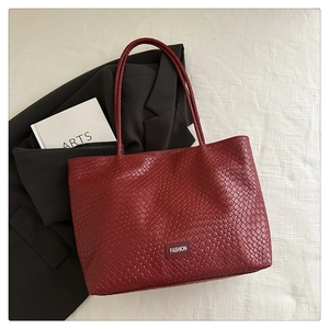 Gros plan du sac cabas bordeaux tressé avec étiquette logo sur un fond minimaliste