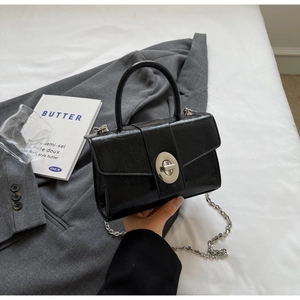 Detail of black faux leather mini square bag with silver twist lock and chain strap