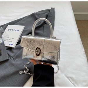 Detail of silver metallic square bag with texture, metal clasp and round handle