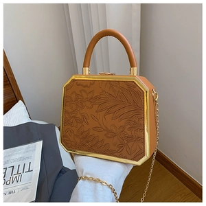 Close-up of embossed floral leather pattern and gold metal frame on a vintage box bag