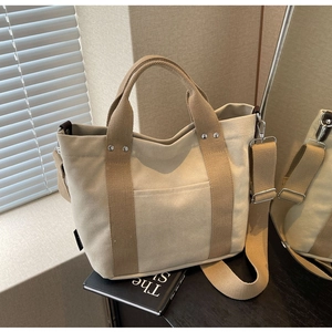 Dettaglio della borsa tote in tela beige con manici marroni e tracolla rimovibile
