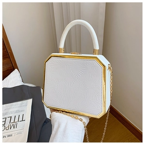 Detail shot of white rigid box bag with floral embossing and golden chain handle