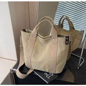 Dettaglio della borsa tote in tela kaki con tracolla regolabile e manici con rivetti argento