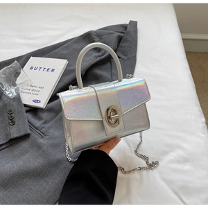 Detail of holographic patent leather mini bag with silver chain strap and twist-lock