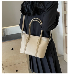 Détail du sac cabas beige minimaliste avec doubles anses et bandoulière sur mannequin