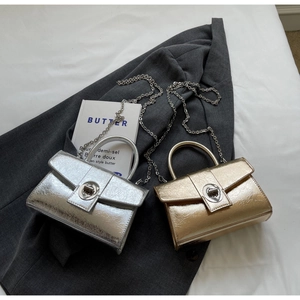 Detailed view of mini metallic satchels with heart twist-lock and chain straps