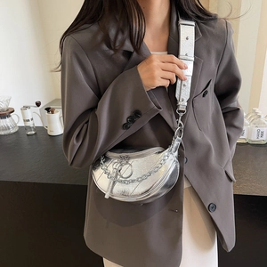 Chic silver metallic crescent saddle bag with bold chain strap worn as a crossbody