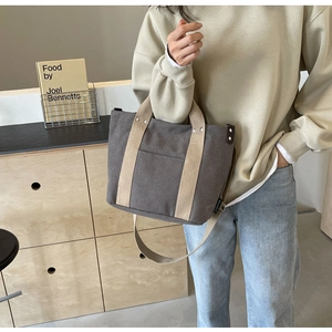 Dettaglio della borsa in tela grigia con manici beige e rivetti laterali in metallo