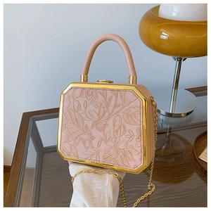 Detail of light pink box handbag featuring 3D floral embossing and gold metal trim frame