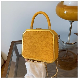 Detail of floral embossed texture on yellow box bag with golden metal frame and top clasp