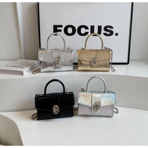 Close-up of four mini patent leather crossbody bags in silver, gold, and black finishes