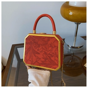 Detail of red octagonal box bag with floral embossing and gold metal chain strap