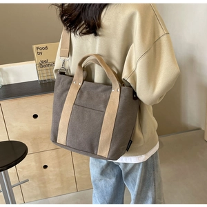 Dettaglio della borsa tote in tela marrone scuro con tracolla beige a contrasto