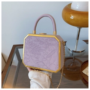 Detail of lavender hardshell bag featuring 3D floral embossing and gold metal trim