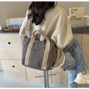 Borsa tote in tela marrone con manici beige e dettagli tasca in un ambiente lifestyle