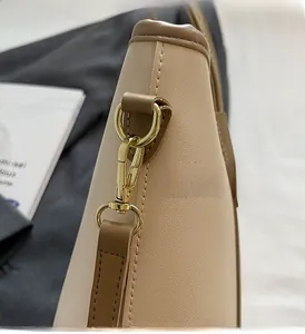 Gros plan du fermoir doré et des coutures contrastées sur un sac cabas en cuir beige