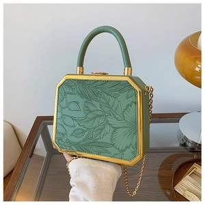 Close-up of green box clutch with 3D leaf embossing and gold metal frame hardware