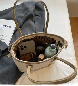 Vue de dessus montrant la grande capacité intérieure du sac cabas beige avec objets
