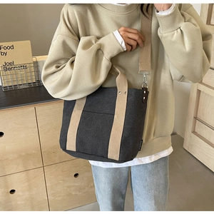 Dettaglio della borsa in tela grigio scuro con manici beige e gancio a tracolla