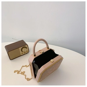 Detailed view of pink structured box bag with floral embossing and gold chain strap
