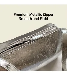 Macro shot of silver metallic leather cylinder bag with smooth hardware zipper detail