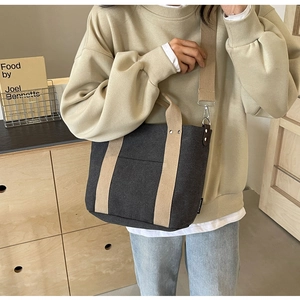 Dettaglio della borsa tote in tela grigia con manici kaki indossata da una modella casual