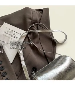 Detail of adjustable leather strap and silver metallic texture on the cylinder bag