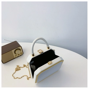 Detail of white geometric box bag with gold metal trim and leather handle
