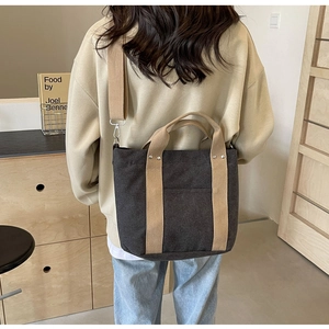 Vista dettagliata della borsa tote in tela grigio scuro con manici beige su una modella