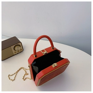Detail of red hexagonal box bag with embossed floral texture and gold chain strap